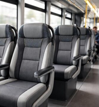 Interior de um ônibus moderno mostrando fileiras de assentos confortáveis e passageiros sentados.