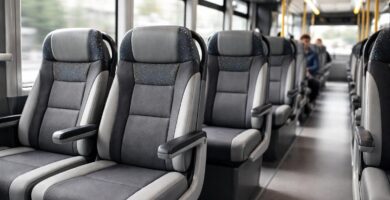 Interior de um ônibus moderno mostrando fileiras de assentos confortáveis e passageiros sentados.