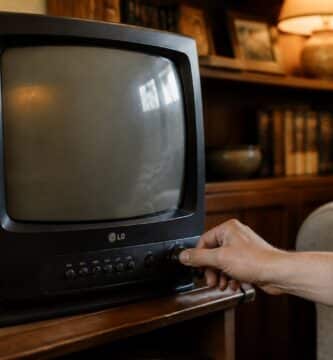 Pessoa ajustando o canal em uma televisão antiga da LG em uma sala aconchegante.