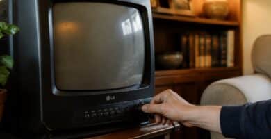 Pessoa ajustando o canal em uma televisão antiga da LG em uma sala aconchegante.